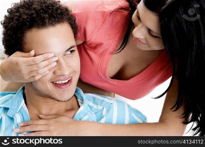 Young woman covering a young man&acute;s eye
