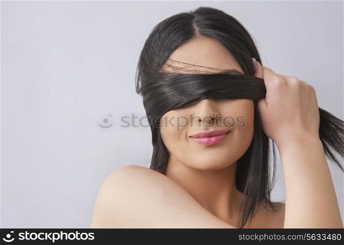 Young woman covering eyes with her hair over colored background