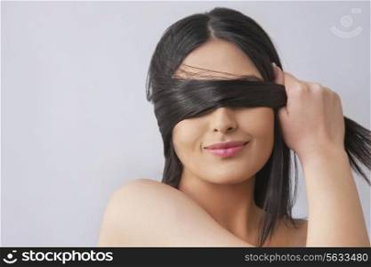 Young woman covering eyes with her hair over colored background