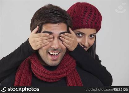 Young woman covering man&rsquo;s eyes