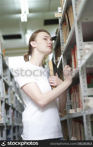 Young woman cranes neck at library shelving