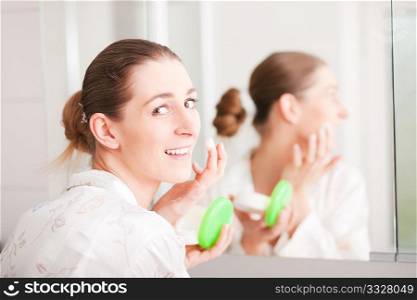Young woman creams her face to keep the skin smooth and soft