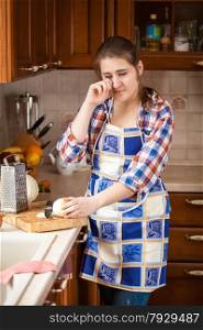 Young woman crying on kitchen while cutting onion