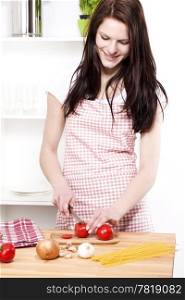 young woman cutting tomato for pasta. young happy woman cutting red tomato for italian spaghetti