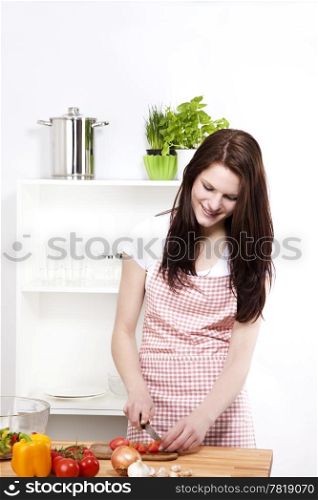 young woman cutting tomatoes. young smiling woman in kitchen cutting tomatoes