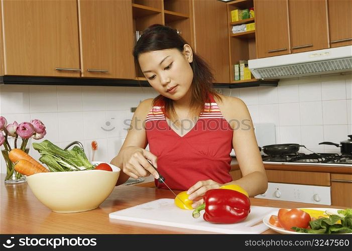 Young woman cutting vegetables at a kitchen counter