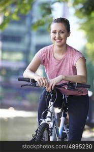 Young Woman Cycling Next To River In Urban Setting
