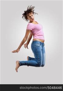 young woman dancing and jumping. pretty modern slim hip-hop style woman jumping dancing on a grey background
