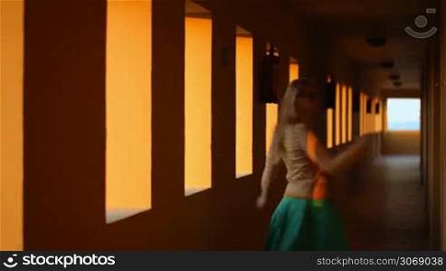 Young woman dancing and spinning around in hotel corridor