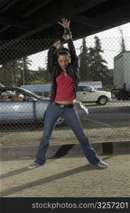 Young woman dancing in front of a chain-link fence