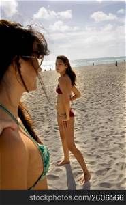 Young woman dancing on beach with friend