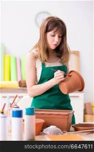 Young woman decorating pottery in workshop