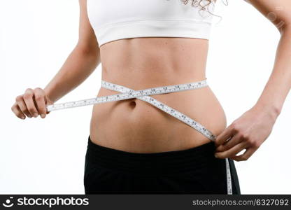 young woman dieting and contemplating weight loss measuring waist with tape on white background