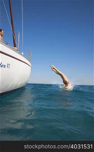 Young woman diving off yacht into sea