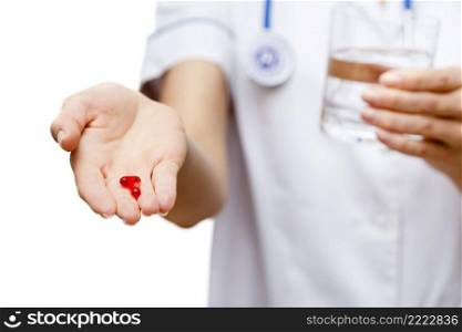 Young woman doctor isolated on white background holding pills. Woman doctor standing on white background