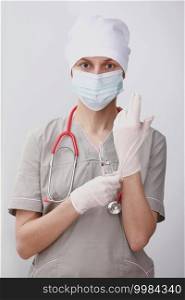 young woman doctor with stethoscope in mask putting on gloves on white background in clinic, hospital. individual protection means. Health care, medical concept.. young woman doctor with stethoscope in mask putting on gloves on white background in clinic, hospital. individual protection means. Health care, medical concept