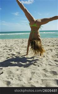 Young woman doing cartwheels in the sand
