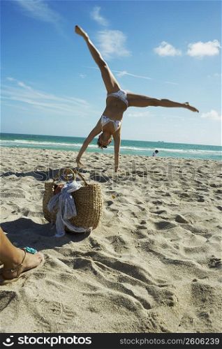 Young woman doing cartwheels on beach