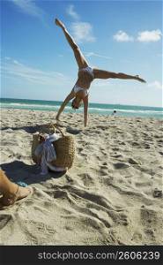 Young woman doing cartwheels on beach