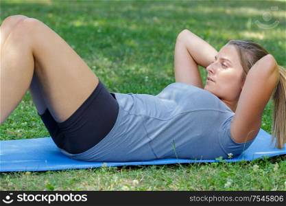 young woman doing crunches outdoors