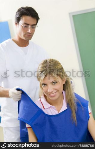 young woman doing dental checkup with x-ray. Dentist is covering her with a protective lead coat