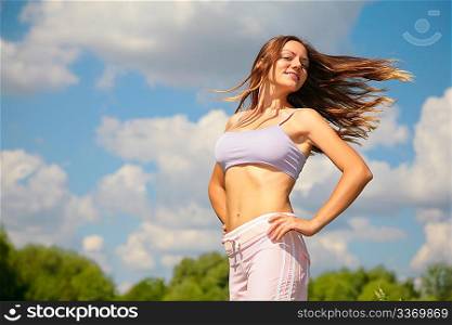Young woman doing exercise in park with windy hair