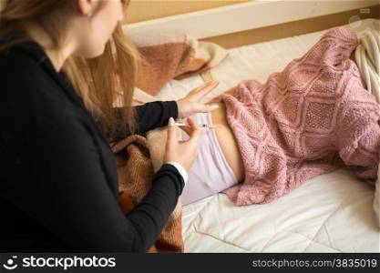 Young woman doing injection in girls bottom lying on bed