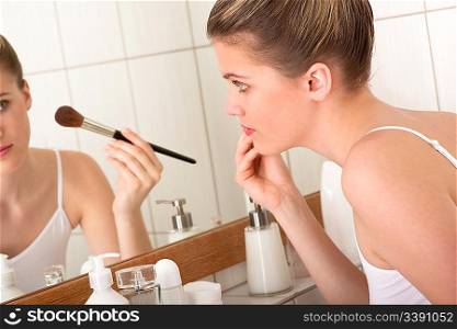 Young woman doing make-up in the bathroom