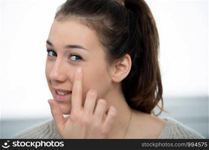 young woman doing makeup while looking at a mirror