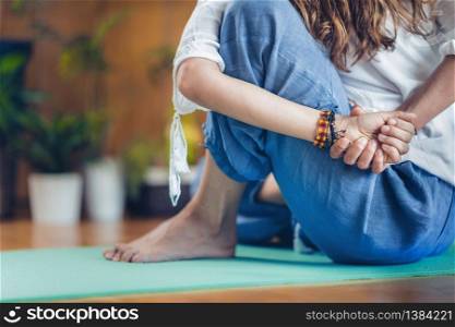 Young woman doing seated spinal twist in Yoga studio. Ardha Matsyendrasana