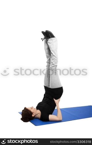 young woman doing shoulder stand. young woman exercising shoulder stand on blue mat