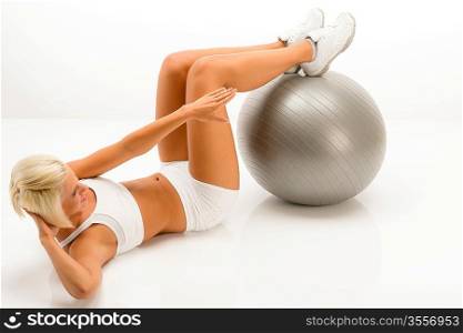 Young woman doing sit-ups on fitness ball lying white floor