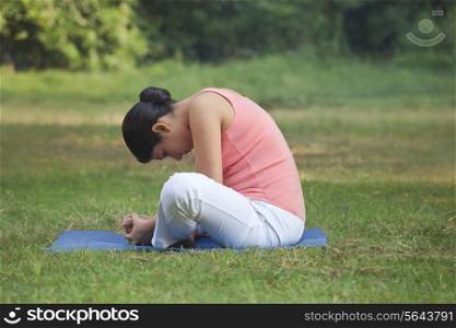 Young woman doing stretching exercise in park