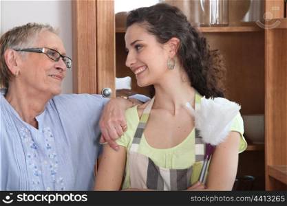 Young woman doing the dusting for an elderly lady