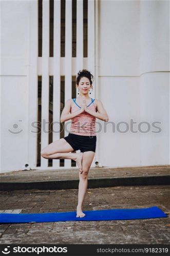 Young woman doing vrikshasana yoga outdoors. Girl doing yoga vrikshasana or tree pose outdoors. Relaxation and vitality yoga concept