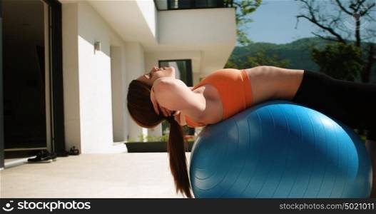 Young Woman Doing Yoga and streching on ball in front of villa