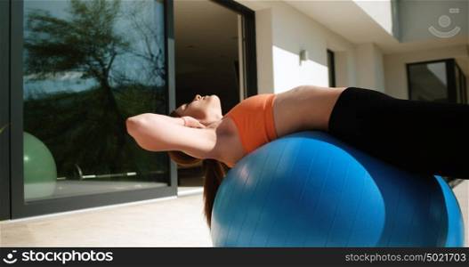 Young Woman Doing Yoga and streching on ball in front of villa