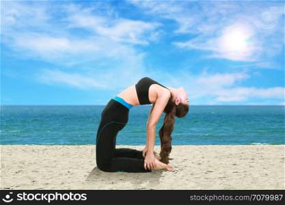 Young woman doing yoga exercise on the beach
