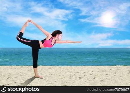 Young woman doing yoga exercise on the beach