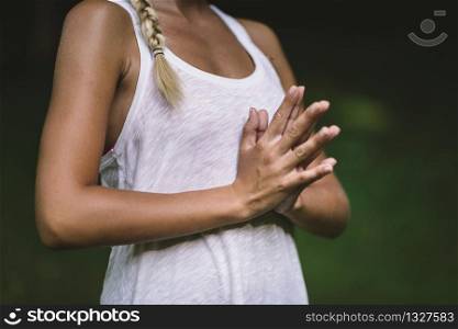 Young woman doing yoga, meditating, hands in prayer position