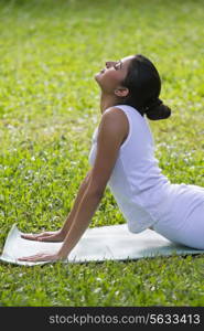 Young woman doing yoga on a lawn