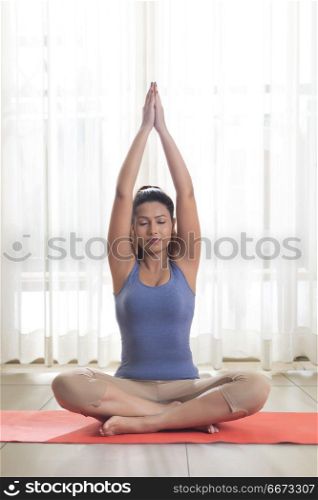 Young woman doing yoga on her exercise mat