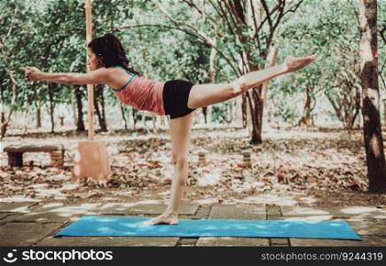 Young woman doing yoga pose warrior III. Spiritual girl practicing yoga Virabhadrasana III outdoors.