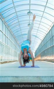 Young woman doing yoga stretching bridge pose outdoors on the bridge. Full Length