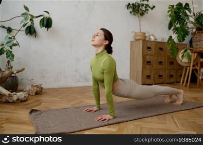 Young woman doing yoga stretching exercise at home. Wellbeing and healthy sport lifestyle concept. Young woman doing yoga stretching exercise