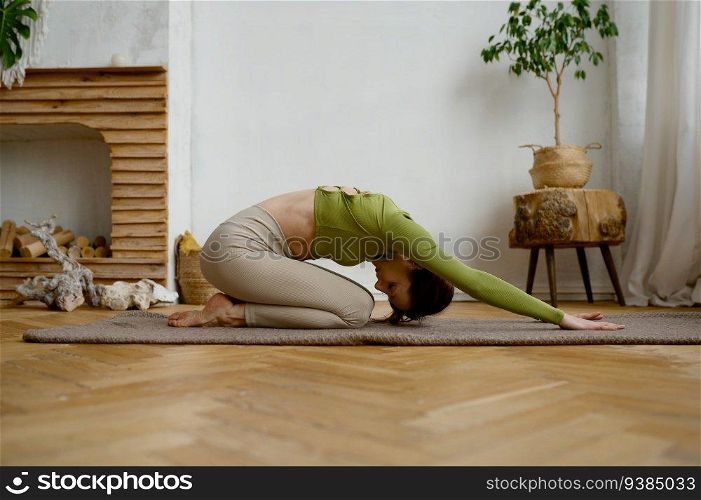 Young woman doing yoga stretching exercise on the floor. Wellbeing and healthy sport lifestyle concept. Young woman doing yoga stretching exercise