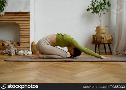 Young woman doing yoga stretching exercise on the floor. Wellbeing and healthy sport lifestyle concept. Young woman doing yoga stretching exercise