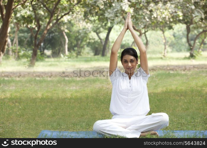 Young woman doing yoga with arms raised