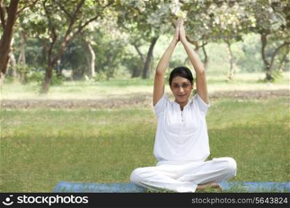 Young woman doing yoga with arms raised