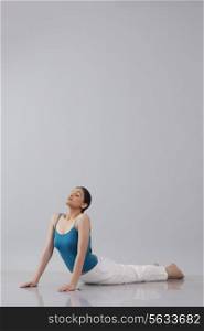 Young woman doing yogic &rsquo;sun salutation&rsquo; isolated over gray background